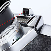 【VOIGTLANDER(福伦达)】Bessamatic 135单镜头反光相机拆解图， 由于有了机身内置测光表，取景器里便有了可显示曝光过度或不足的指针，为使摄影者眼睛不离开取景器便可知道当前的光圈和速度，福伦达 Bessamatic“De Luxe”首创了光圈和速度读取窗，通过这“T”型的小窗口便可将镜头上的光圈和速度值投射到取景器内，摄影者一目了然。